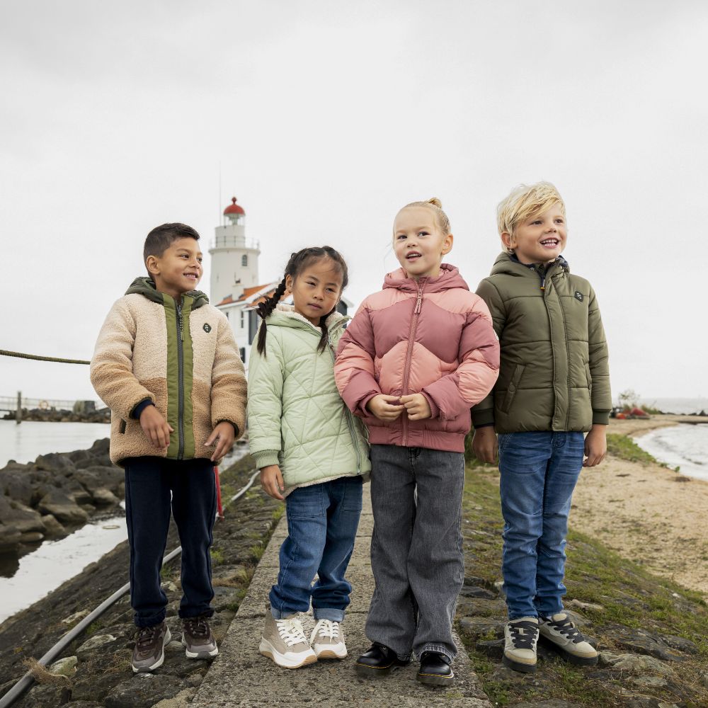 Four children stood outside by the sea