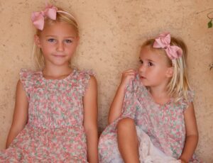 Two girls wearing floral dresses and pink bow headbands by Phase Eight Childrenswear