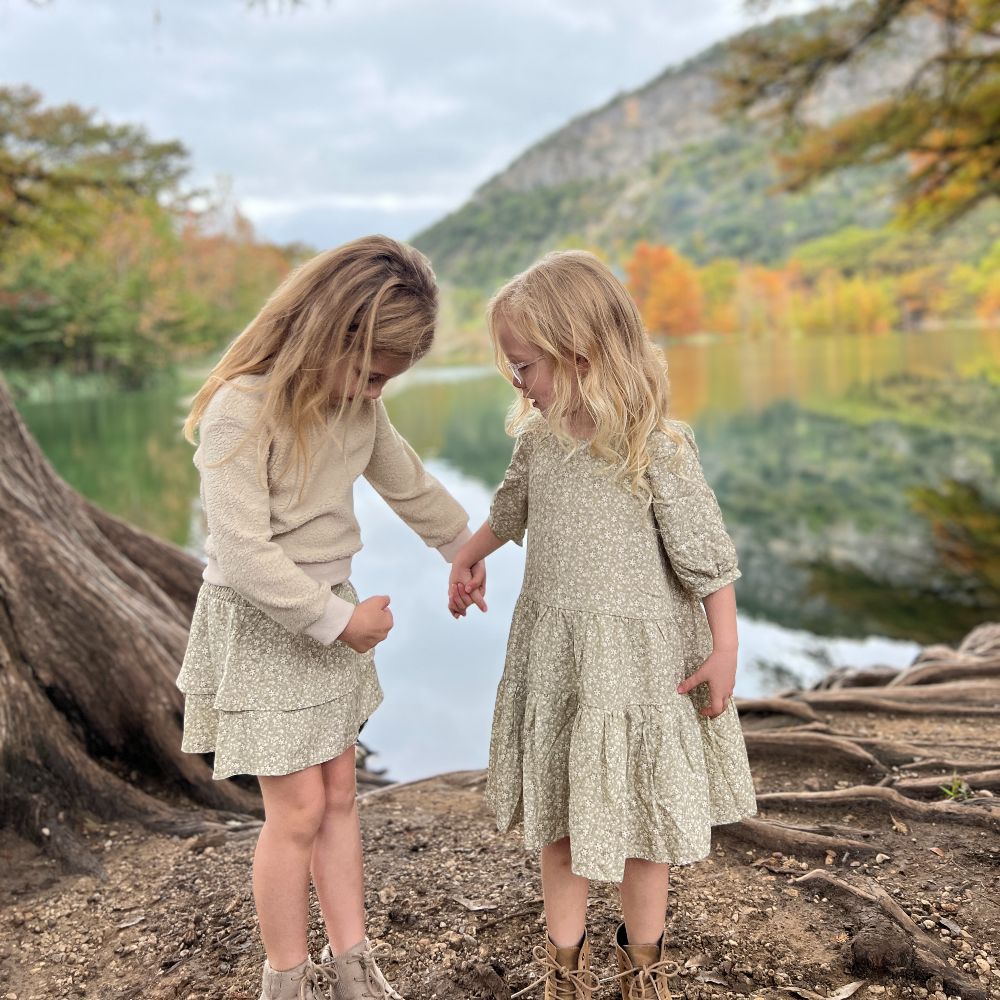 Two young girls holding hands beside a lake 
