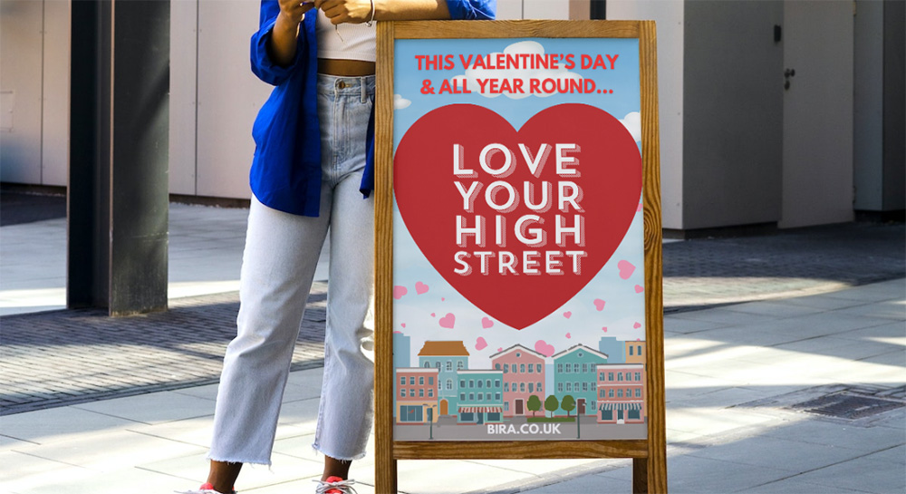A woman stood next to a love your high street sign