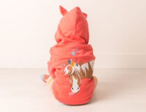 The back of a child sat on the floor wearing am=n orange hoodie with a Bella the Horse motif on the back