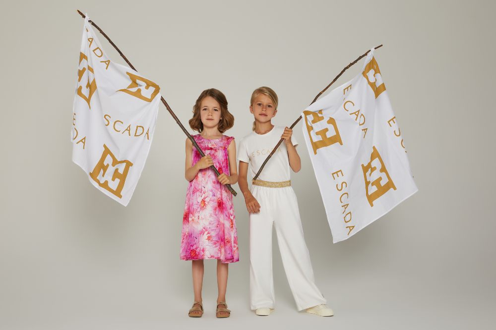 Two girls holding Escada flags wearing outfits from the new Escada Girls range