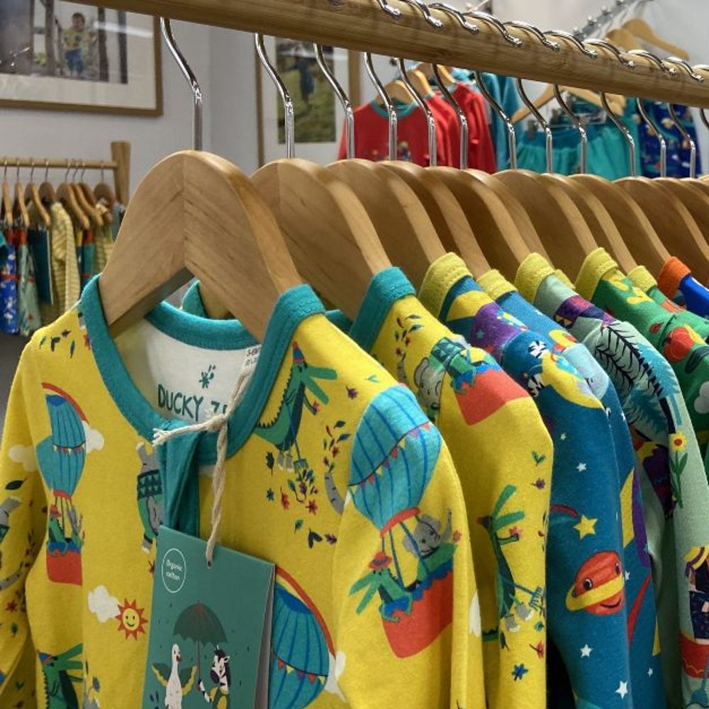 Brightly coloured children's clothes hung on wooden rails