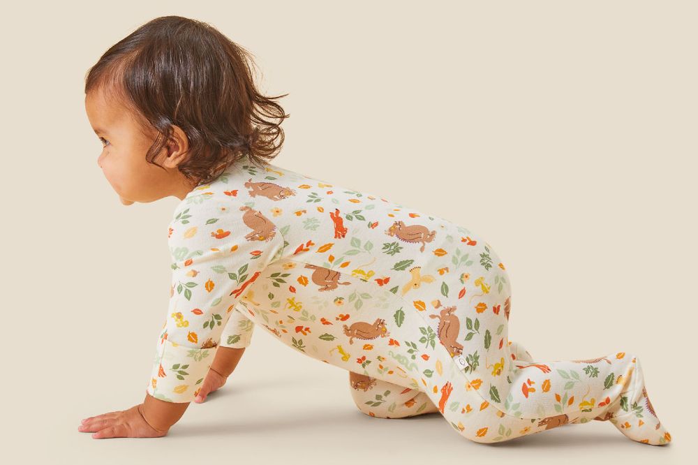 A baby crawling wearing a babygro from MORI's Gruffalo Collection