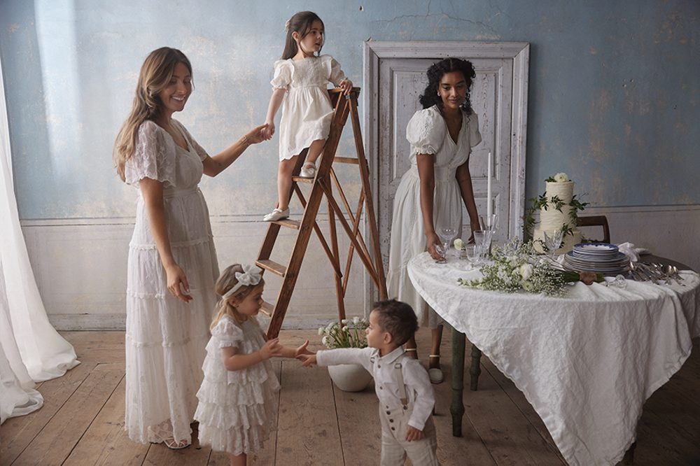 Women and young children in a room wearing wedding clothes by Newbie