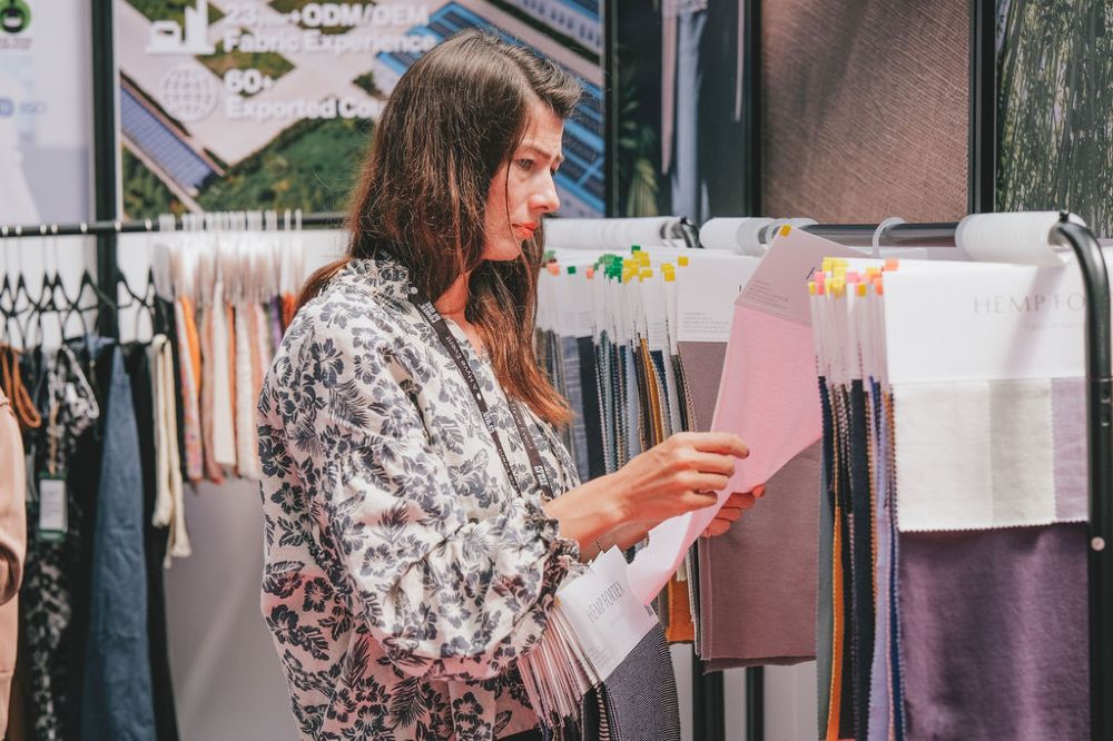 A woman stood on a stand at Source Fashion looking at fabric samples 