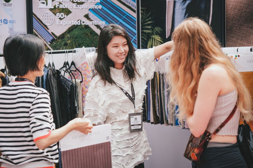 A woman showing customers fabric samples on a stand at Source Fashion 
