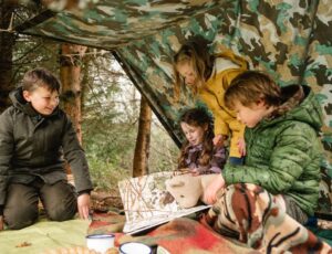 Children outside in a den looking at a map