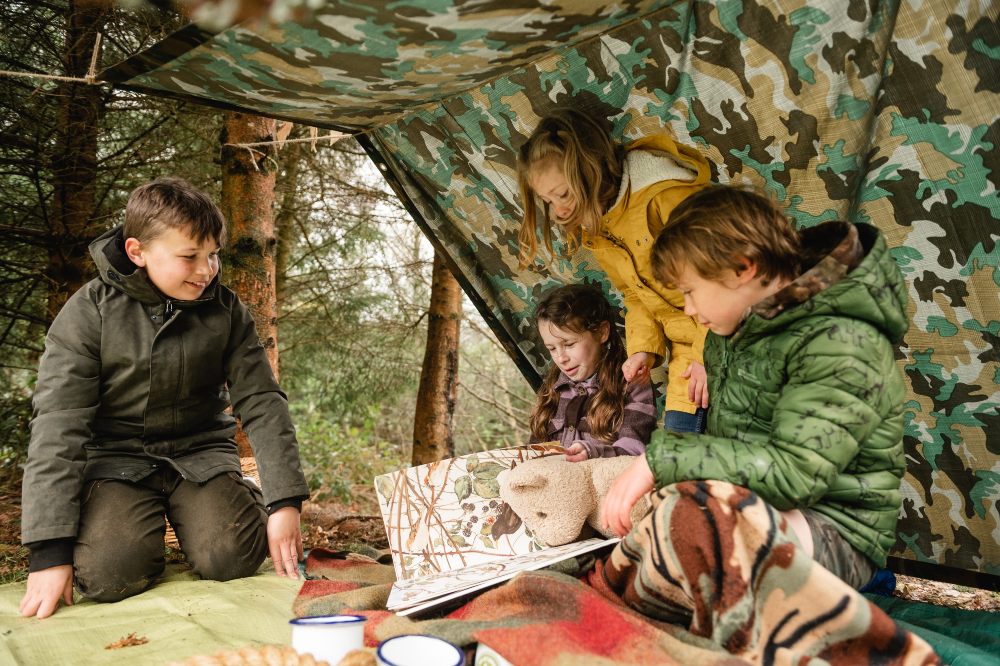 Children outside in a den looking at a map
