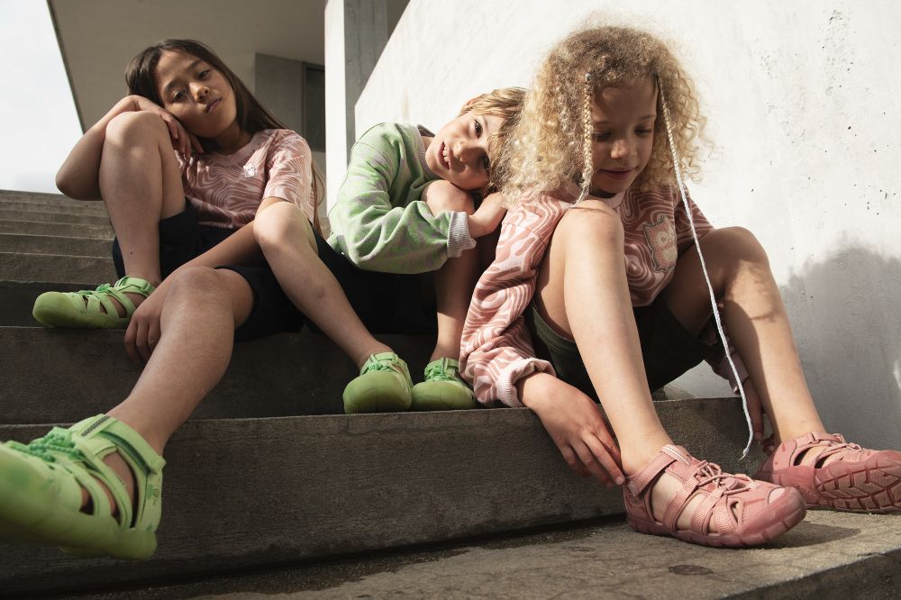 Three children sat outside on some steps wearing Seacamp sandals by KEEN and namuk
