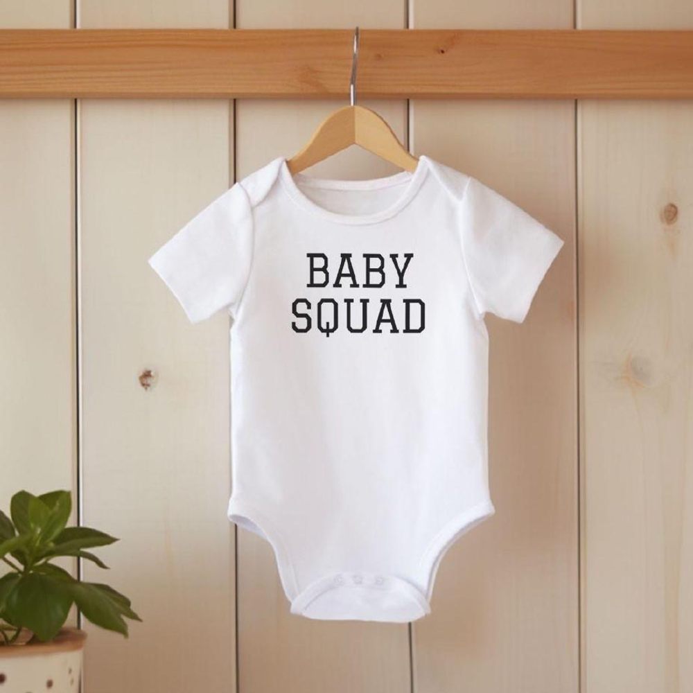 A white babygro with Baby Squad on the front hung on the wall