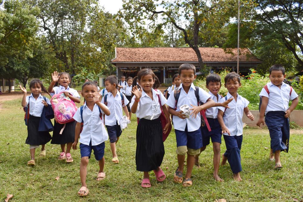 A group of Cambodian children wearing school uniform stood outside 