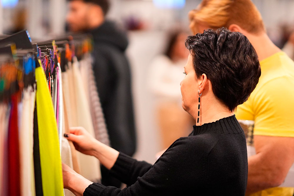A visitor looking through a rail of clothing on an exhibition stand
