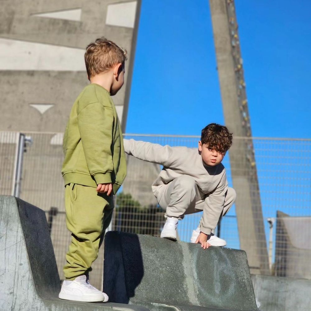 Two boys in tracksuits stood on concrete seating 