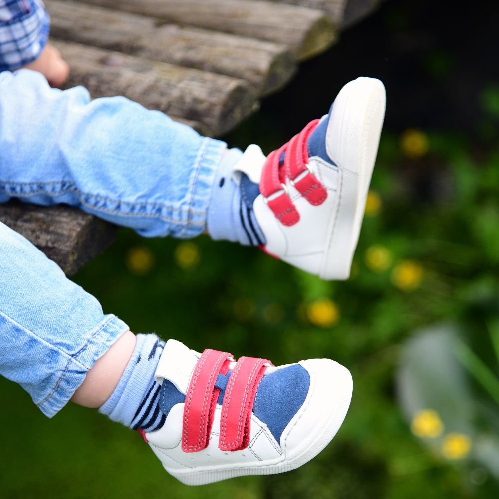 A child's legs stuck out wearing jeans and a pair of trainers 