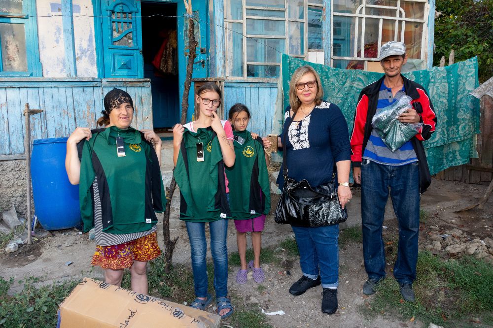 Rosalind Bluestone MBE, founder of Goods For Good, stood outside beside children holding up clothing