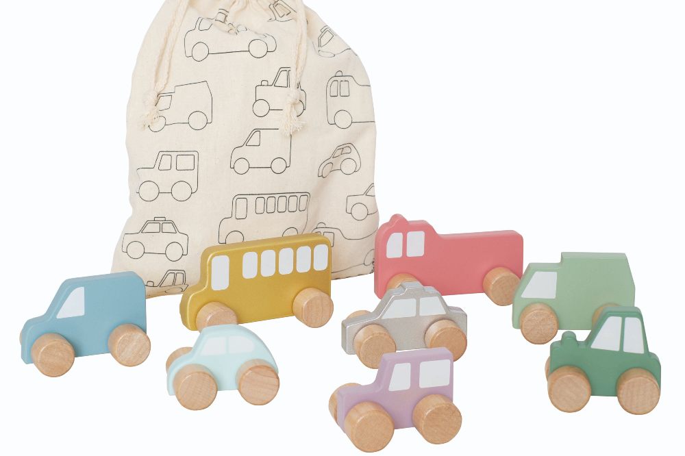 Different coloured wooden cars and trucks beside a cloth gift bag