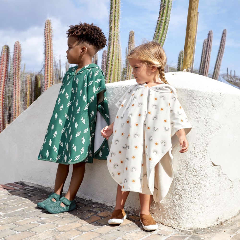 Two children stood beside a white rock wearing ponchos 