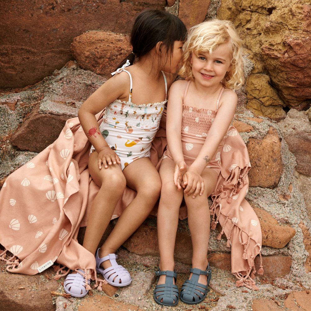 Two children sat on a rock in swimwear 