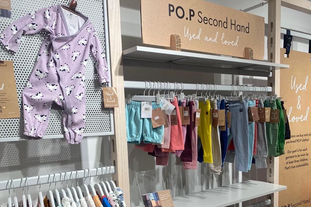 An in-store stand full of children's clothes hanging on rails