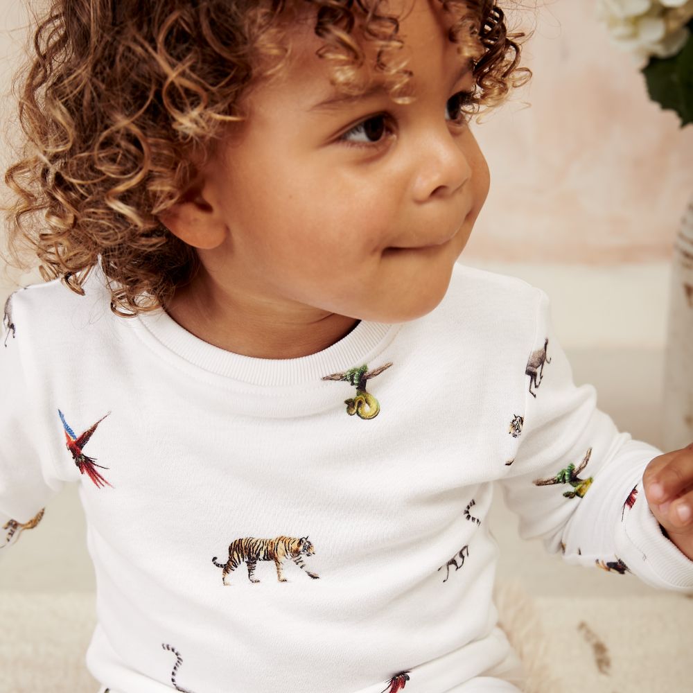 A young child wearing a white top with animal prints on it by Rosa & Blue 