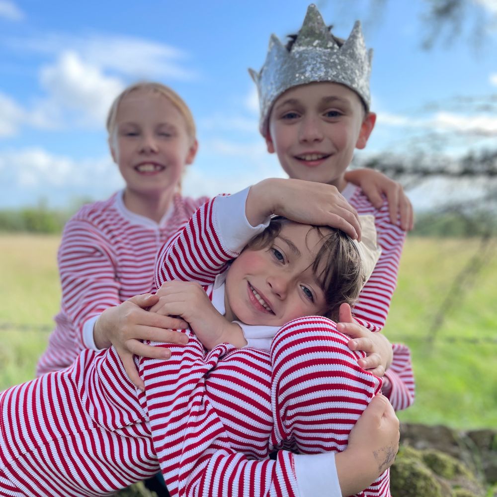 Three children outside wearing red and white striped outfits 