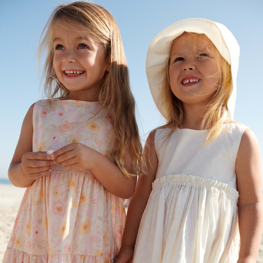 Two young girls in sundresses stood outside 