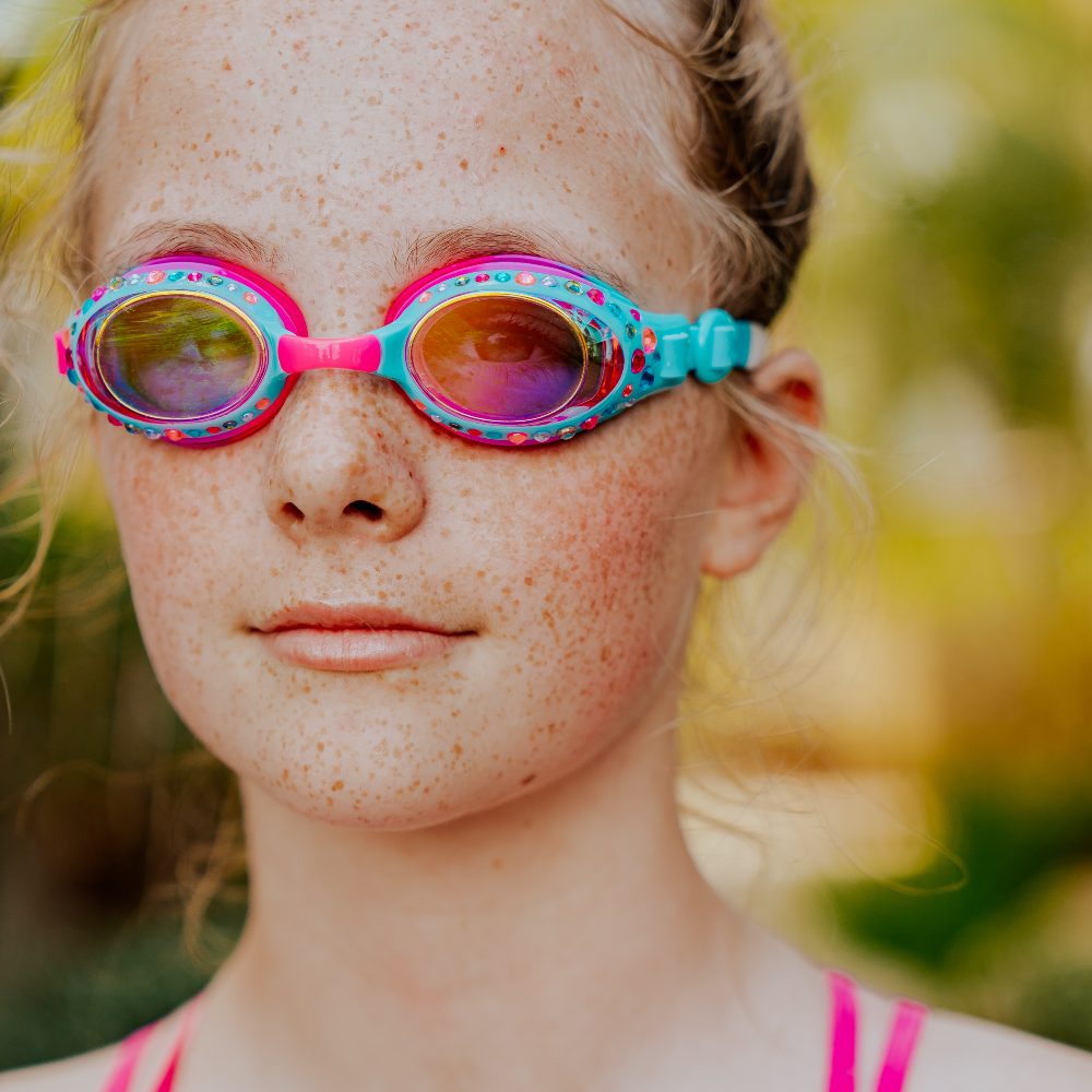 A young girl wearing pink and blue sparkly swim goggles by Bling2o