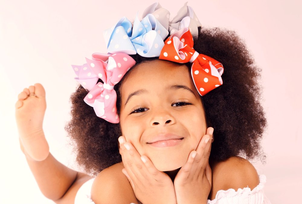 A young girl smiling with different coloured bows in her hair