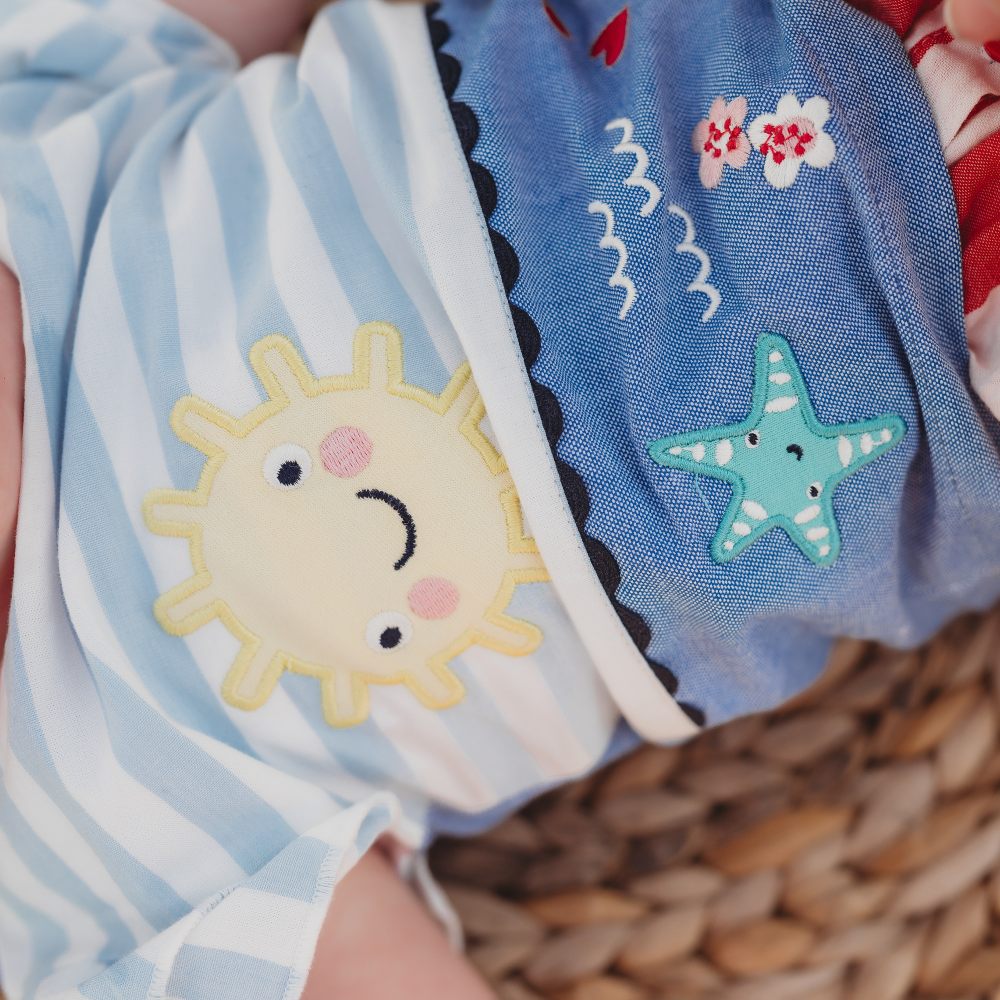A close up of a baby's T-shirt with a sun and sea creature appliques 