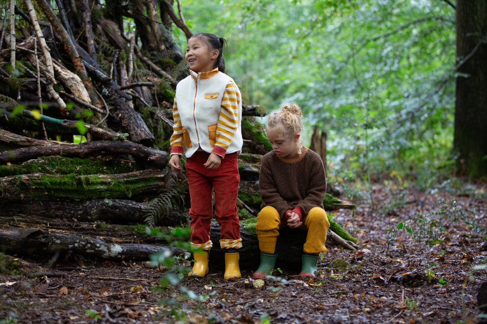 Two children in a wood wearing Fairtrade natural rubber waterproof boots by Little Green Radicals
