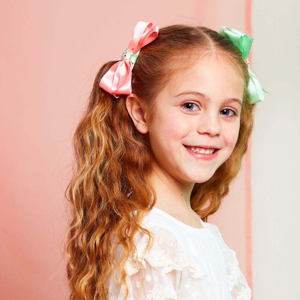 A young with a pink and green bow in her hair 