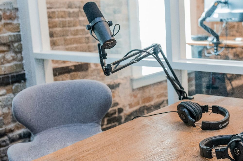 A desk set up for a podcast with a microphone and headphones