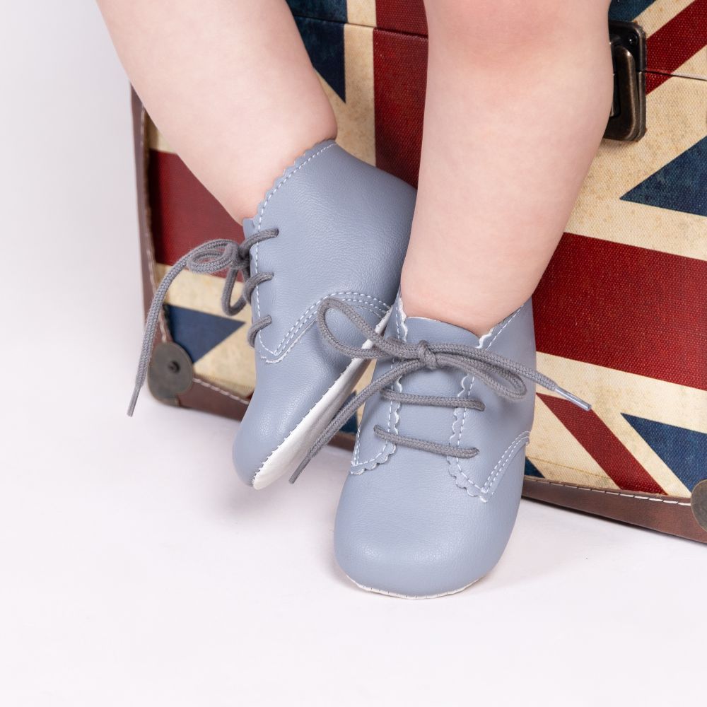 A picture of a child's legs and feet in pale blue leather shoes against a Union Jack box 