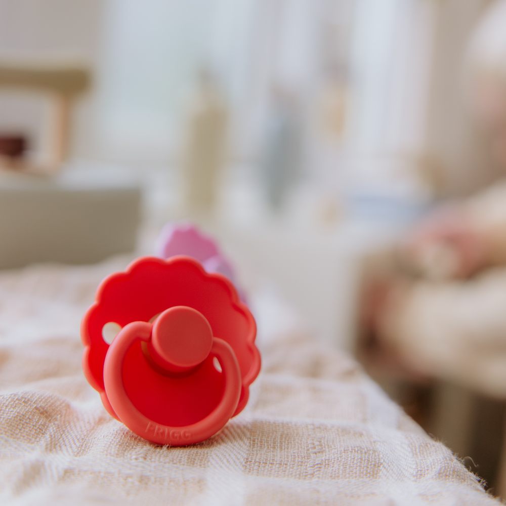 A red poppy shaped pacifier displayed on a table 