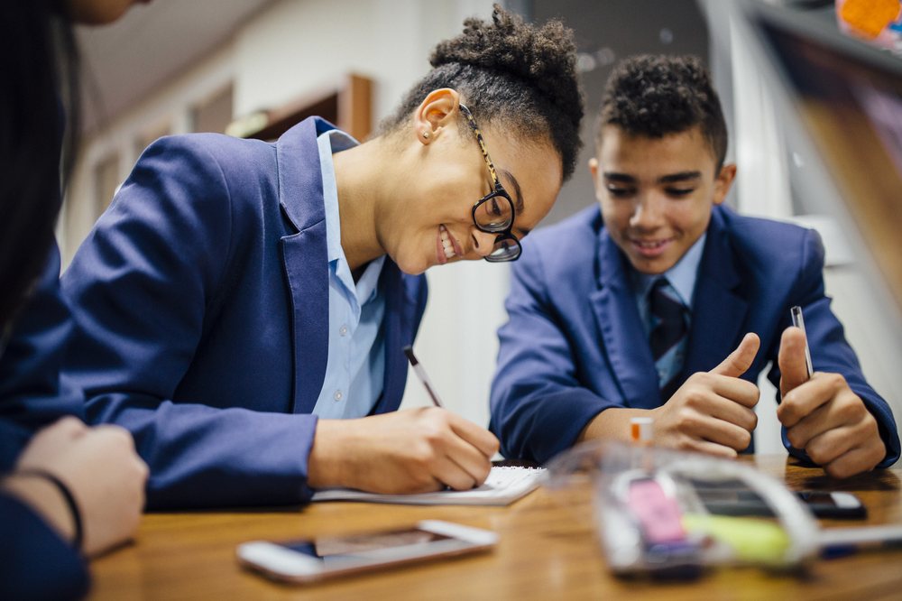 A girl and a boy in school uniform working at a desk 