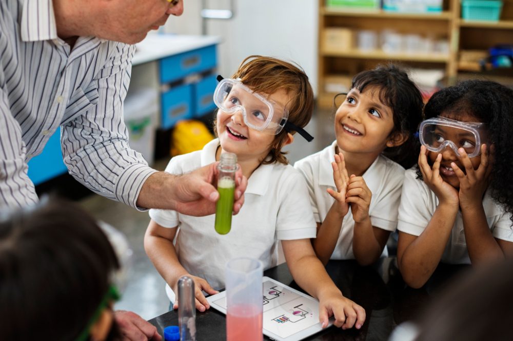 Young school children in a classroom with a teacher doing a science lesson 