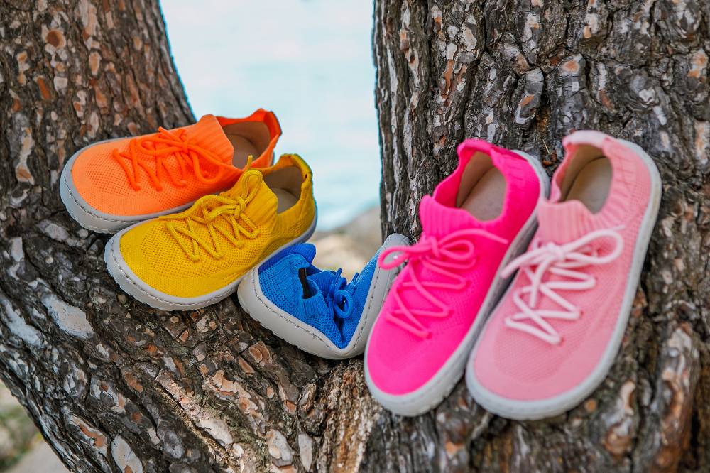 Brightly coloured barefoot shoes by Froddo displayed in a tree