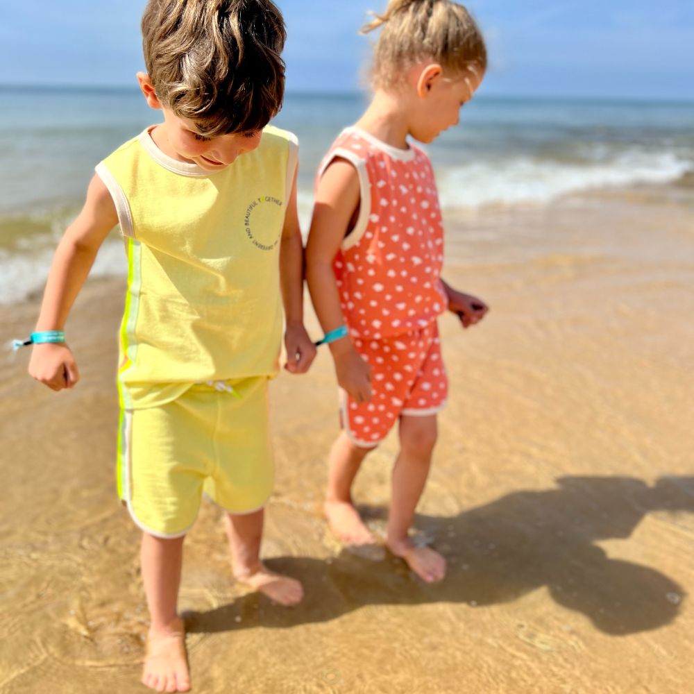 Two children in shorts and T-shirt walking on a beach 