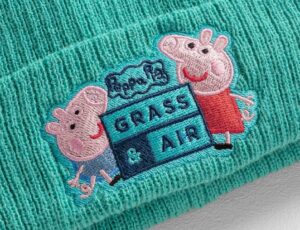 A close up of a mint green Grass & Air beanie hat with a Peppa Pig embroidery on the front