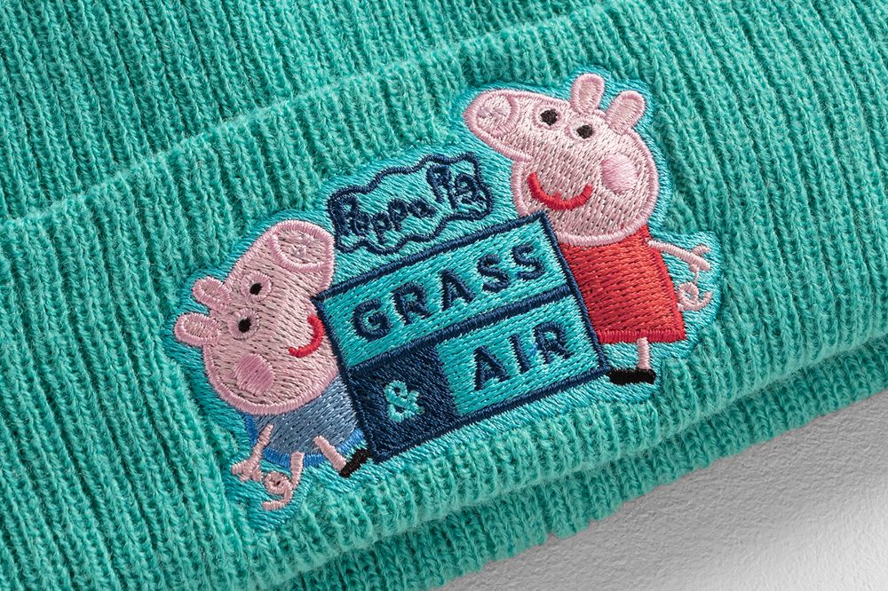 A close up of a mint green Grass & Air beanie hat with a Peppa Pig embroidery on the front