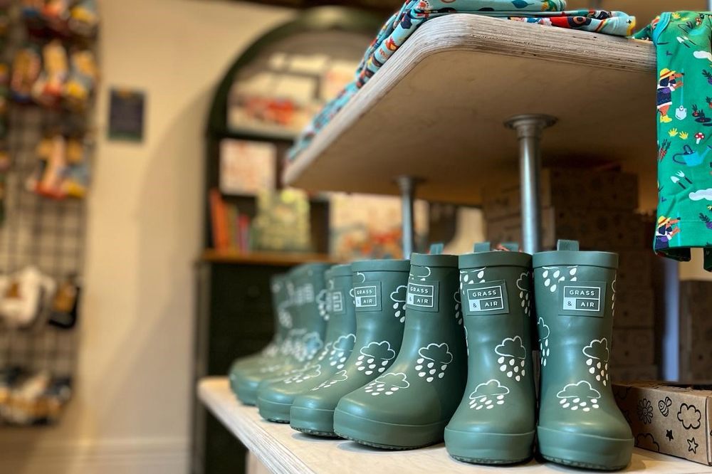 Green children's wellington boots displayed on a shelf in Margo's Petersfield