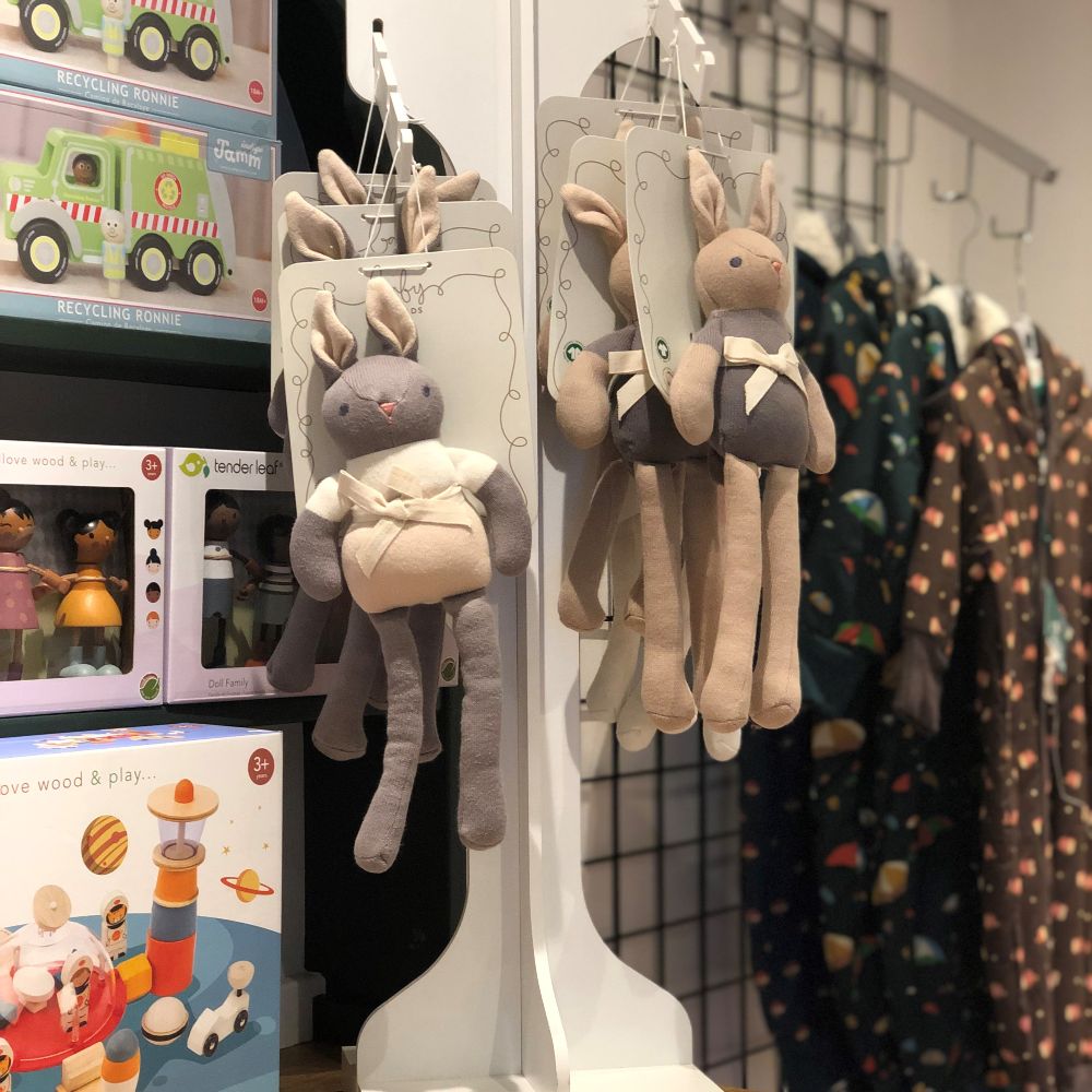 Children's toy rabbits hung on a display beside children's clothes and toys 