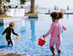 Two young children playing in a pool wearing animal character sunsuits from the new My Little Swimsuit range