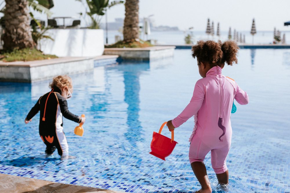 Two young children playing in a pool wearing animal character sunsuits from the new My Little Swimsuit range