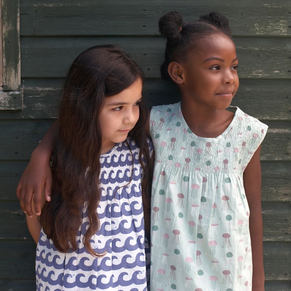 Two girls in summer dresses stood together outside 