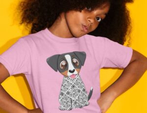 A young girl with her head tilted and her hands on her hips wearing a pink T-shirt with a dog on the front by Zuma the Dog