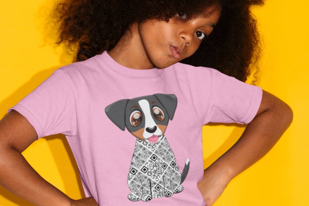 A young girl with her head tilted and her hands on her hips wearing a pink T-shirt with a dog on the front by Zuma the Dog