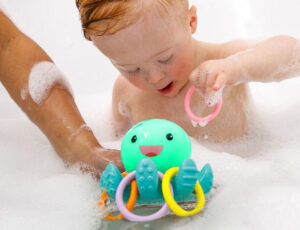 A young boy playing with the Infantino light up octopus ring catcher toy in the bath