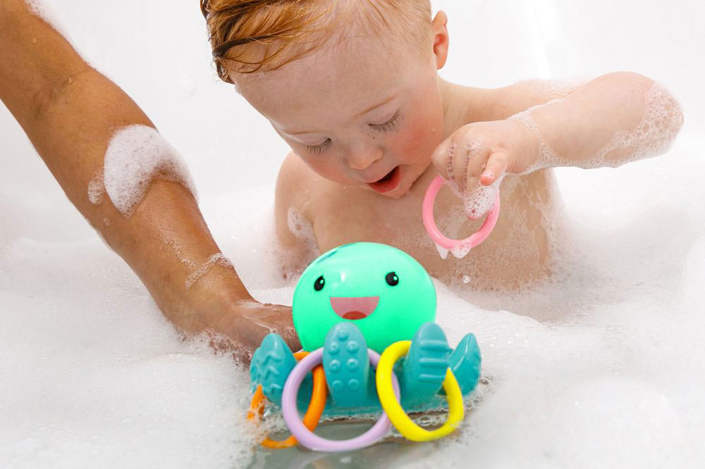 A young boy playing with the Infantino light up octopus ring catcher toy in the bath